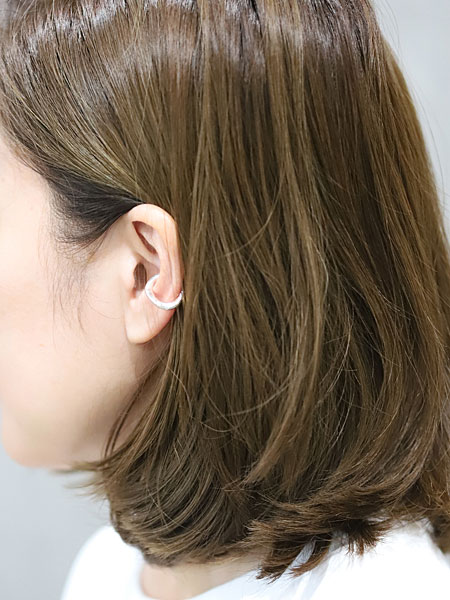 存在感のあるイヤーカフが女性の耳元に映え、シンプルなスタイルのアクセントになっている着用画像。