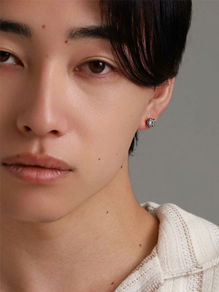 耳元にクリアストーンが光る様子がわかる、正面から写した男性の着用画像。