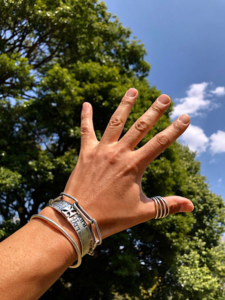 デザイナーがバングルやブレスレット、リングを合わせて着用したシルバーアクセサリーのコーディネート画像。