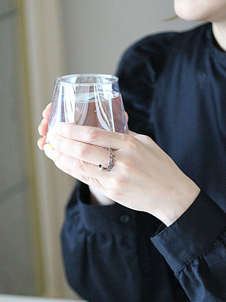 花とヘビをモチーフにしたリングが女性の手元を華やかに彩る自然な着用イメージの画像。