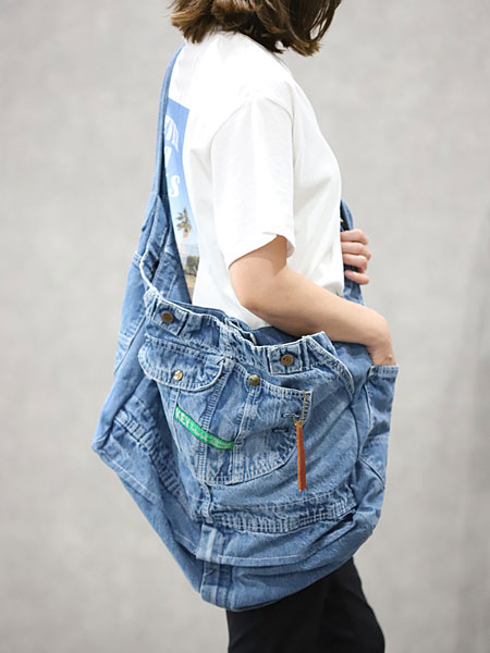 女性がデニムのリメイクバッグを肩にかけた着用画像で、体を包み込むような大きめのシルエットが印象的です。
