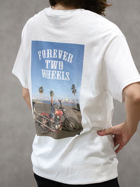 女性がOTO Tシャツを着用した背面画像で、少年とカスタムバイクのプリントがアメリカンヴィンテージな雰囲気を演出しています。