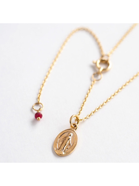 繊細な彫刻と色味のコントラストが美しい、トップのマリアモチーフとルビーチャームをアップで撮影。