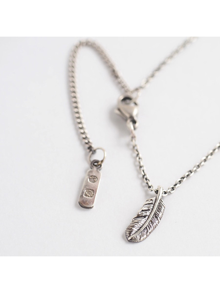 フェザートップとチェーンのエンドに付いたブランドタグを一緒に写した画像。