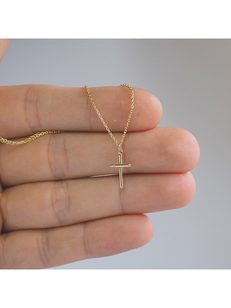 クロス ネックレスのトップを手に持ってサイズ感を伝える写真。