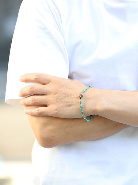 男性がサンクのターコイズ ブレスレットを正面から着用している様子、深みのあるブルーグリーンが手元に爽やかさを添えている。