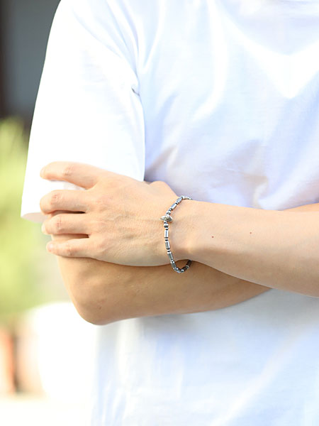 男性がサンクのシルバー ブレスレットを正面から着用している様子、上品な輝きが手元を引き締める。