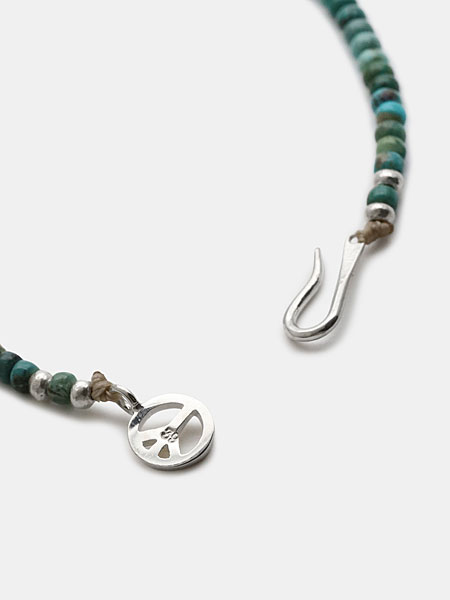 Sunkuオリジナルのピースマークの留め具とフック部分をアップで撮影、ブランドらしい遊び心が感じられる。