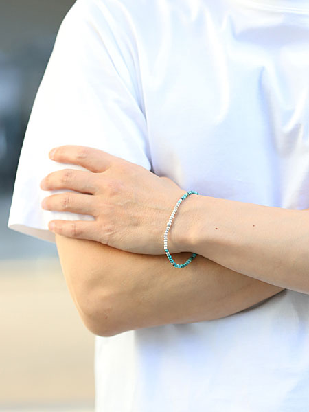 男性がSunkuのターコイズ シルバー ピース フック ブレスレットを着用した正面画像、深みのあるブルーグリーンが手元に爽やかさを添えている。