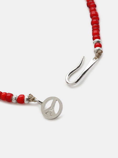 Sunkuオリジナルのピースマークの留め具とフック部分をアップで撮影、ブランドらしい遊び心が感じられる。