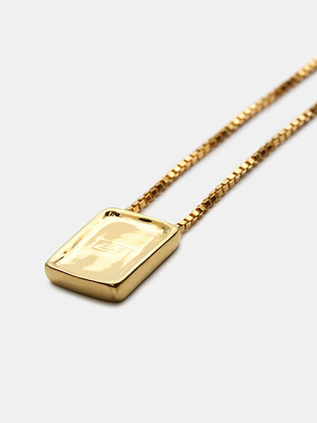 ゴールドカラーのペンダントトップを近くから写した画像で、上品な光沢と刻印のディテールが見える。