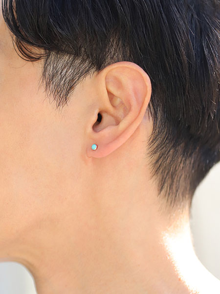 男性が横向きで着用している様子で、小ぶりなターコイズが自然に耳元に馴染んでいる。