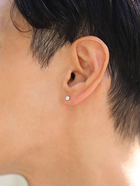 男性が横向きで着用している様子で、小ぶりなオパールが自然に耳元に馴染んでいる。