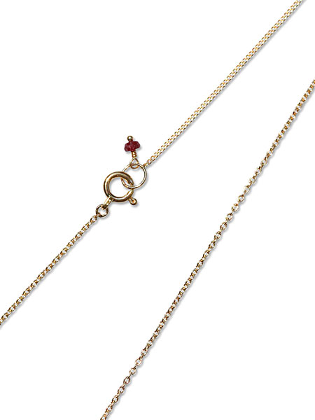 チェーンの先に小さなルビーチャームが付いた様子をアップで撮影した写真。
