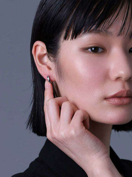 女性が正面から着用していて、柔らかい光を放つカット面が上品に見える自然なスタイリング写真。