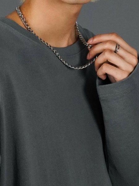 チェーンを軽く持ち上げて、デザインを見せている着用シーン。