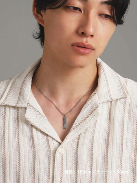 男性がネックレスを着用した姿を正面から写しており、シンプルな服装に自然と馴染むプレートデザインのバランスがよく分かる。