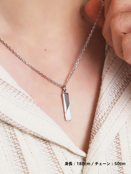 男性が着用した状態でチェーンを指で持ち上げ、プレートの質感がわかりやすいように見せた画像。