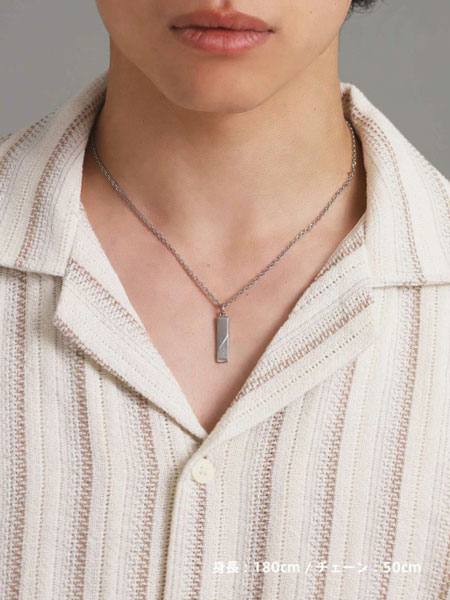 男性がネックレスを着用した姿を正面から写しており、シンプルな服装に自然と馴染むプレートデザインのバランスがよく分かる。