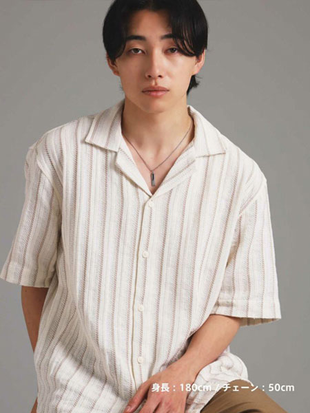 男性の全体をやや遠くから写した画像で、シンプルなネックレスがコーデ全体に馴染む雰囲気が分かる。