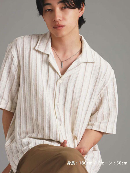 男性の全体をやや遠くから写した画像で、シンプルなネックレスがコーデ全体に馴染む雰囲気が分かる。