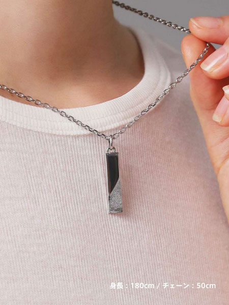 女性がチェーンを指で軽く持ち上げ、プレートのサイズ感と質感がわかりやすく見えるようにした画像。