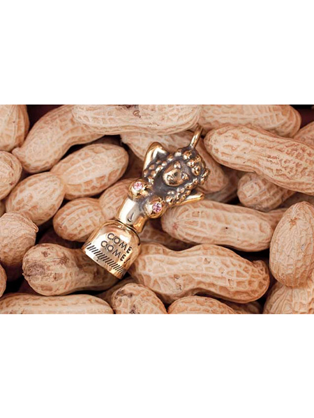 COME COME BELLをピーナッツの上に置いたディスプレイ画像で、チャームのサイズ感と質感が自然に伝わる。
