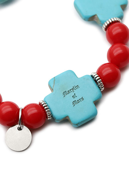 ターコイズクロスの裏面に刻まれたブランド刻印をクローズアップし、丁寧な作りが感じられる写真。