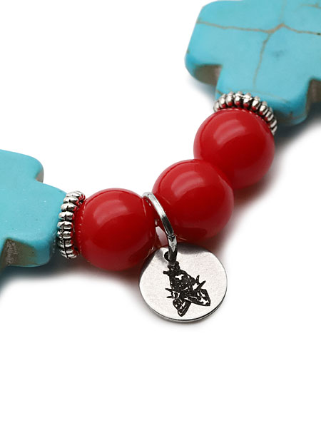 ビーズの間にセットされたブランドチャームのアップで、刻印や金属の質感まで見えるように撮影されている写真。