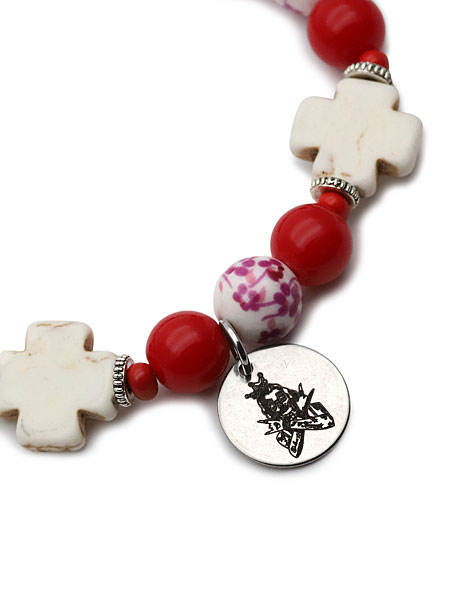 ビーズの間にあるブランドチャームをアップで撮影し、ブランドマークや金属の質感が確認できる画像。