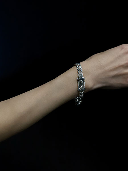 手元でカーブチェーンとヴィクトリアン調バックルが映え、程よいボリューム感が伝わる着用アップ画像。